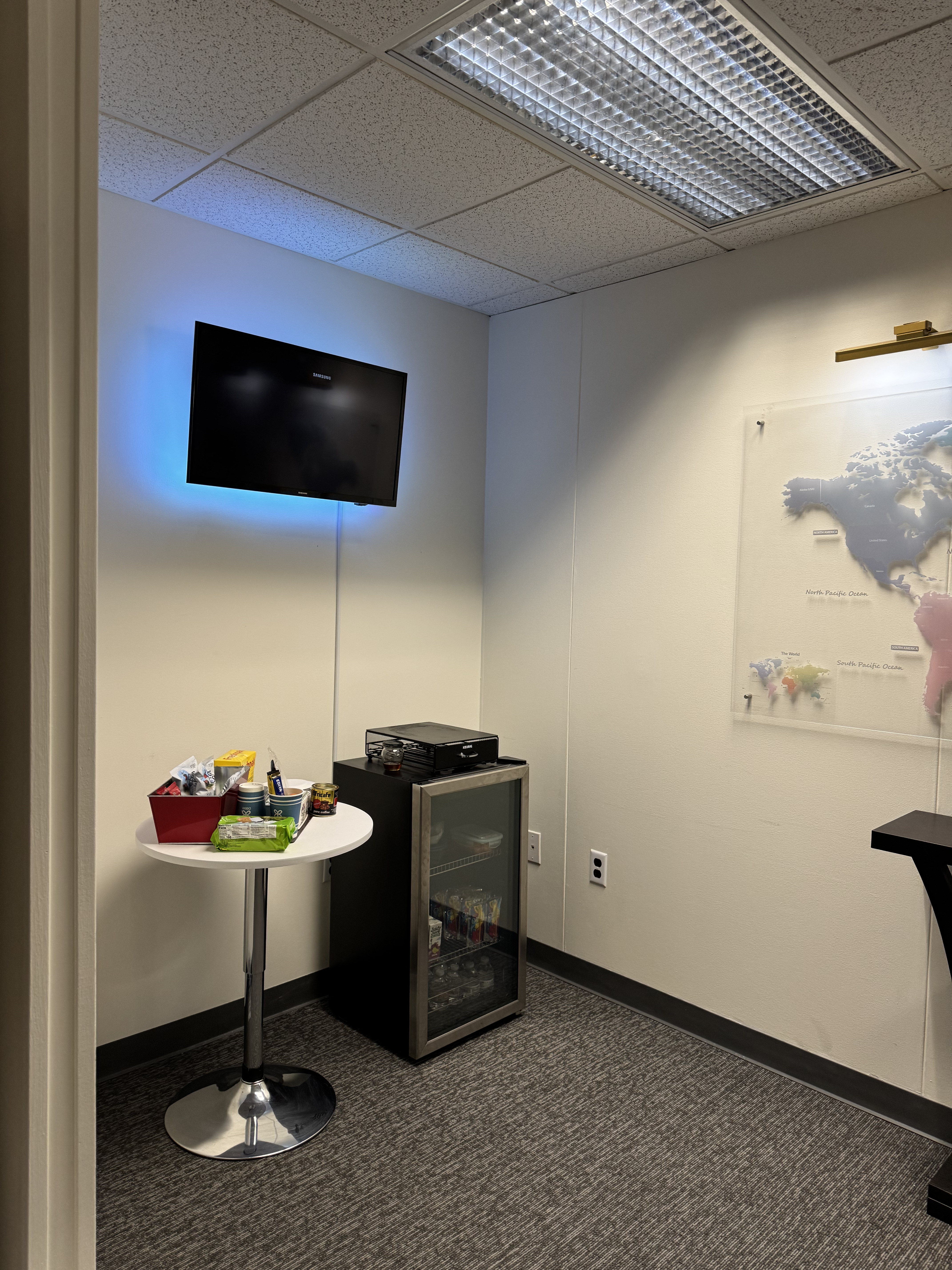 Snack table and mini fridge next to wall-mounted TV